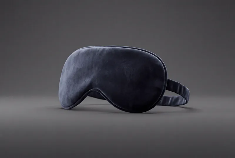 Одиночная фигурная маска для сна, выполненная как чистый 3D-объект с бархатистой матовой текстурой, контактной тенью и сдержанным студийным освещением
