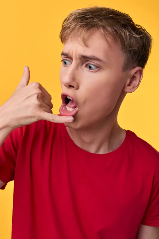 Hand gesture, call, phone, surprised expression, red shirt, yellow background conveying contact and outreach, casual vibe, clear communication cue for inquiries, customer support concept, and visual