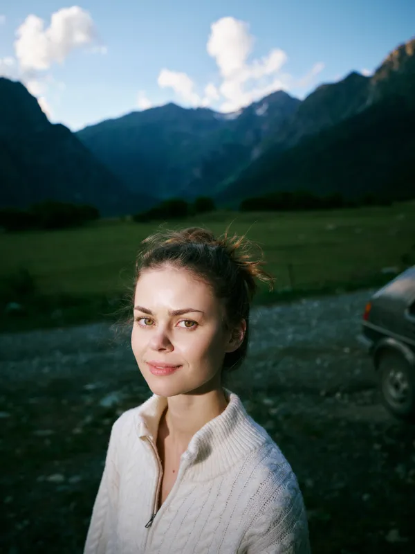 Woman outdoors in a knit sweater, mountains in the background, serene mood and natural light, ideal for travel, lifestyle, or nature photography scenes