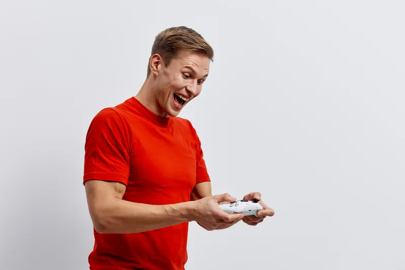 excited man playing video game use controller isolated on white background casual red t-shirt entertainment concept
