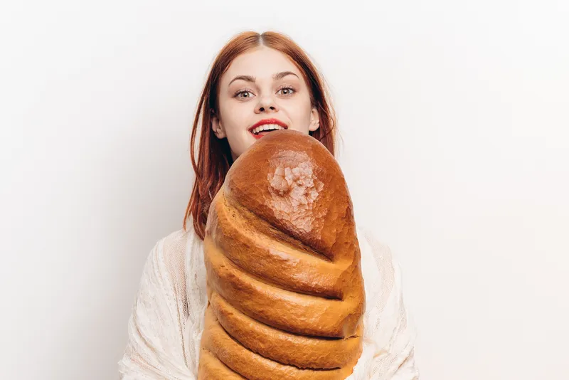 Эмоциональная женщина с большим комком муки, продукт, хлеб, светлый фон