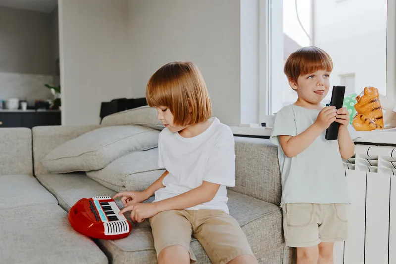 Playful children enjoying music together, creating a joyful atmosphere at home, surrounded by a cozy living space with bright colors.