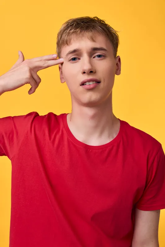 Thinking gesture head, redshirt and yellowbackground convey concentration and curiosity in a modern casual studio setup, showcasing confident mood and focus for creative, educational or tech themed