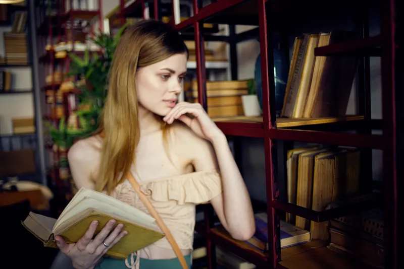 Женщина читает книгу в ресторане во время отпуска, занимаясь самообразованием