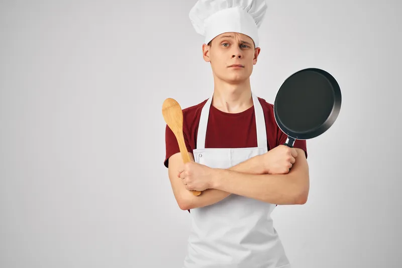 Повар-мужчина с кухонной утварью на светлом фоне, профессиональный ресторанный работник