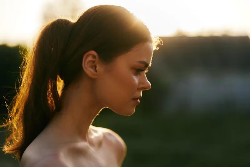 A serene portrait of a young woman with long hair in profile, capturing a moment during sunset, evoking emotions of tranquility and beauty