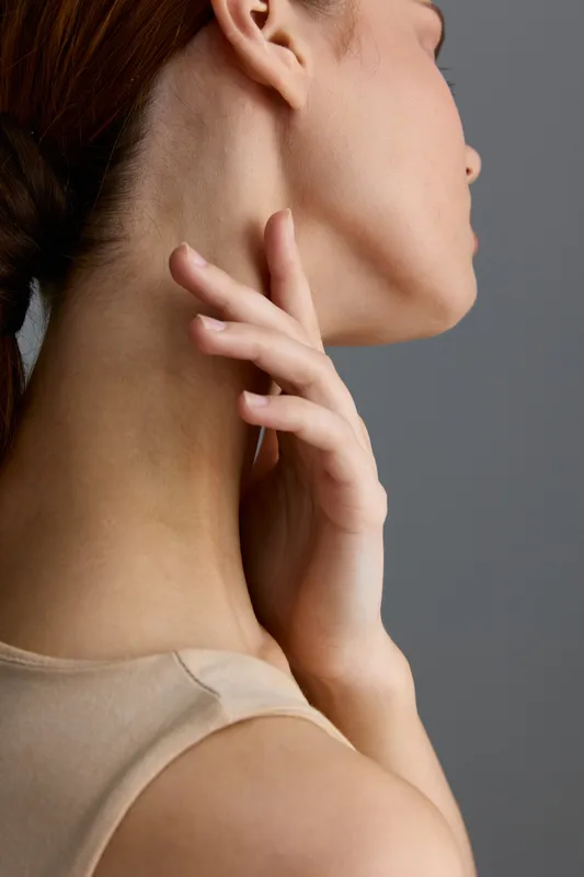 beauty woman with smooth skin touching her neck, natural makeup, soft lighting, beige outfit, close-up portrait, minimalistic style