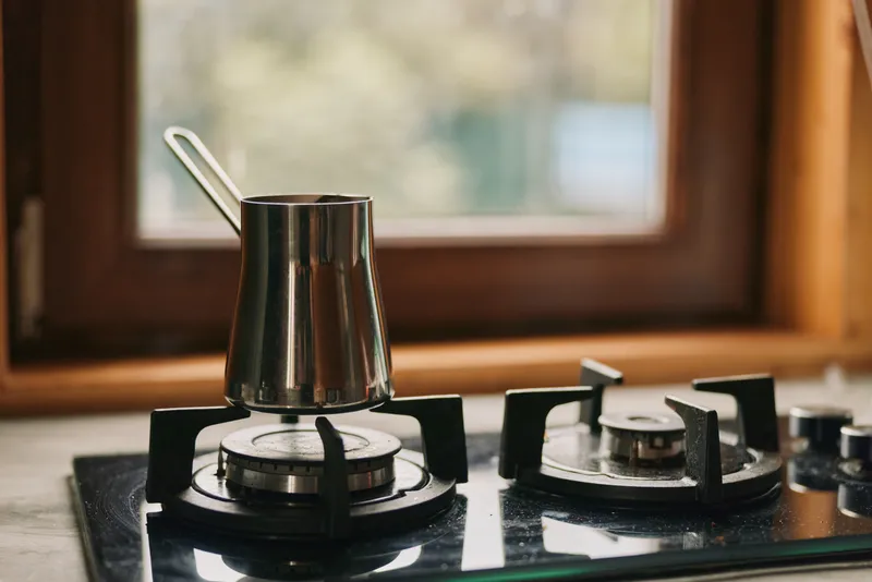 stove burner kitchen scene shows a metal kettle on a gas hob with a steady flame creating a warm cooking atmosphere for home chefs and inviting aroma fills the air