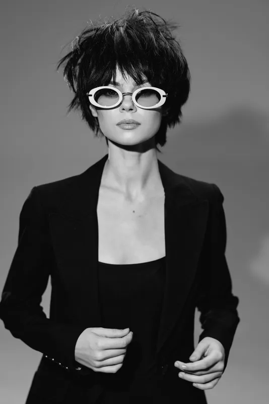 Stylish woman with short hair and white sunglasses wearing black blazer in black and white portrait