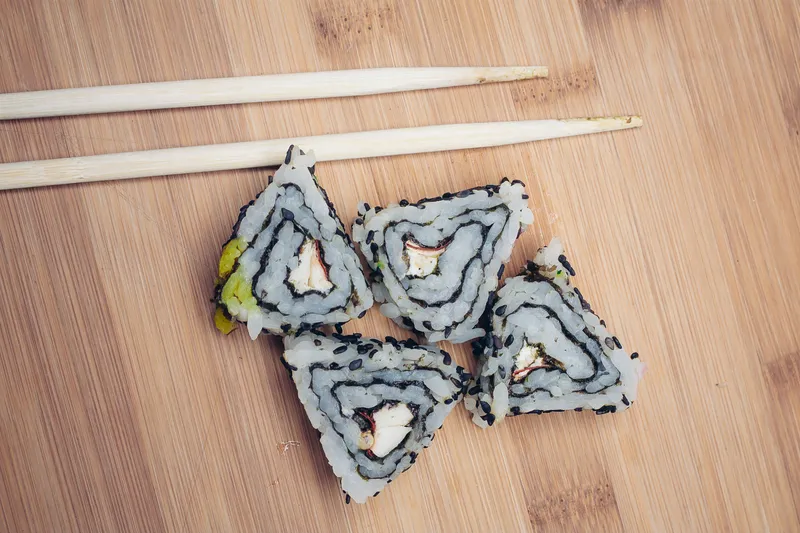 Роллы суши, палочки для еды, деревянная доска, японская кухня
