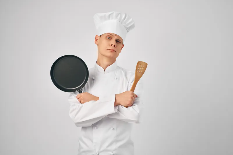 Мужчина в форме повара работает на профессиональной кухне, оказывая услуги