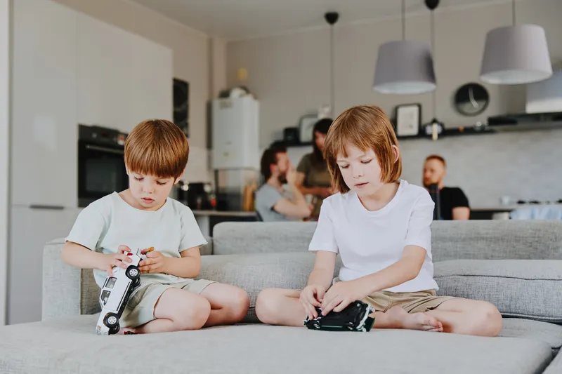 Two boys playing with toy cars in a cozy living room, evoking a sense of joy and childhood innocence in a modern, bright space.