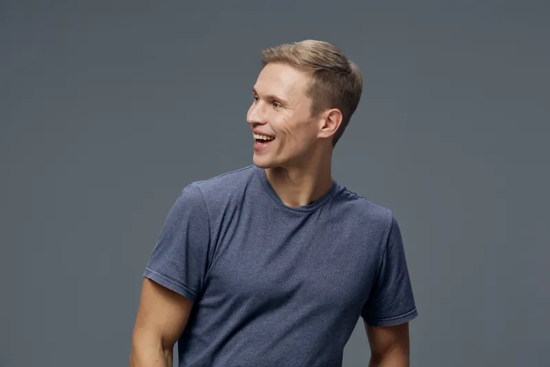 cheerful young smiling man in casual blue t-shirt looking aside isolated on gray background digital nomad technology remote work concept