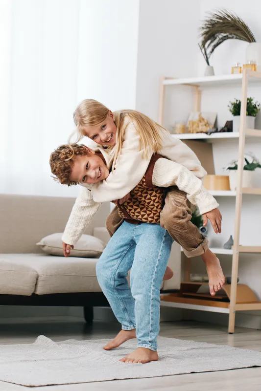 Authentic moment of playful siblings in a cozy home, capturing lighthearted joy, everyday school readiness, and healthy lifestyle in a candid lifestyle scene.