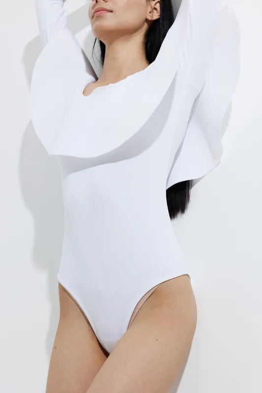 woman sport fitness wearing white athletic bodysuit, stretching with raised arms, demonstrating healthy active lifestyle and body strength, studio lighting