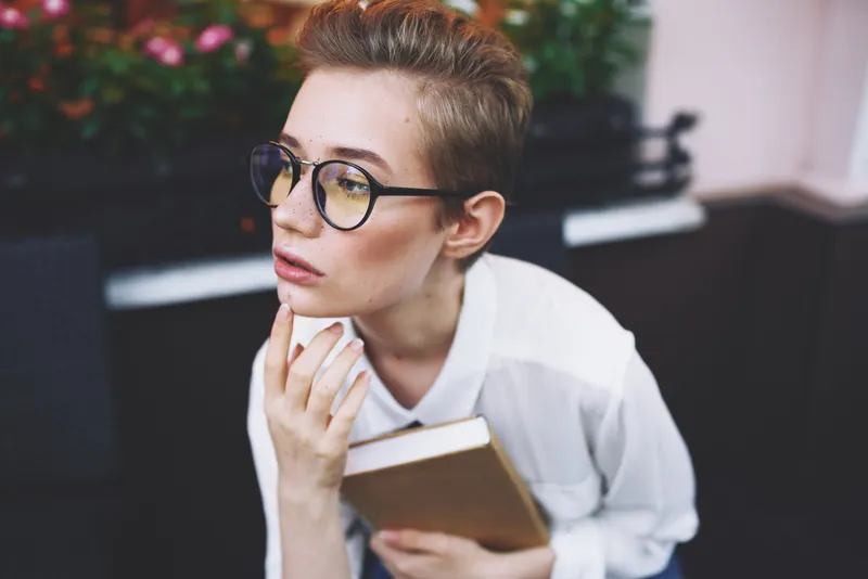 Коротко стриженная женщина с книгой в руках читает