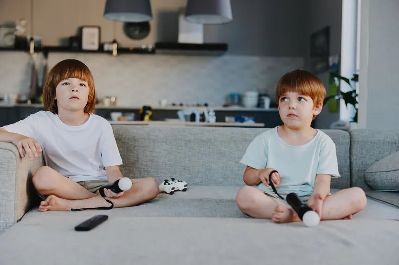 Two focused boys enjoying video games at home, immersed in a fun experience together. Engaging atmosphere with gaming controllers and cozy surroundings.