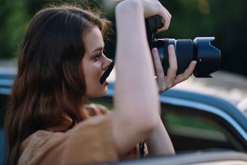 Young woman capturing moments with a camera, showcasing creativity and passion in outdoor settings, with soft lighting and a relaxed vibe.
