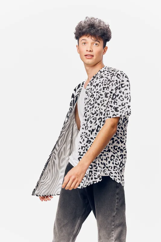 young man wearing leopard print shirt posing in studio with casual jeans and white background, stylish male fashion look