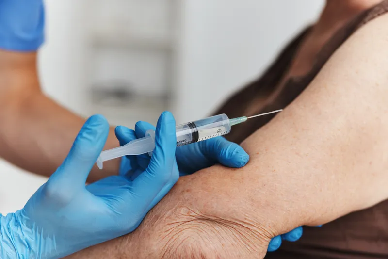 Врач делает инъекцию в руку женщины, паспорт вакцинации от COVID-19