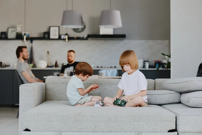 Two cheerful children playing together on a cozy sofa in a modern living room, showcasing a relaxed family atmosphere and joyful interaction.
