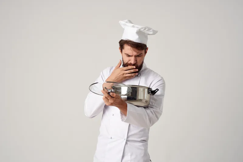 Весёлый повар с кастрюлей в руках на кухне, работа по приготовлению еды