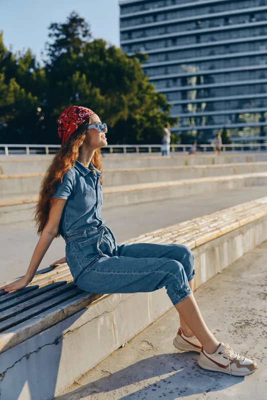 lifestyle woman wearing modern boho-western denim outfit with street style sitting outdoors in natural light film color tones