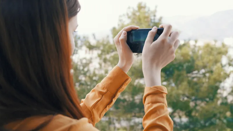 Женщина с телефоном в руке фотографирует природу на камеру во время отпуска на фоне пейзажа
