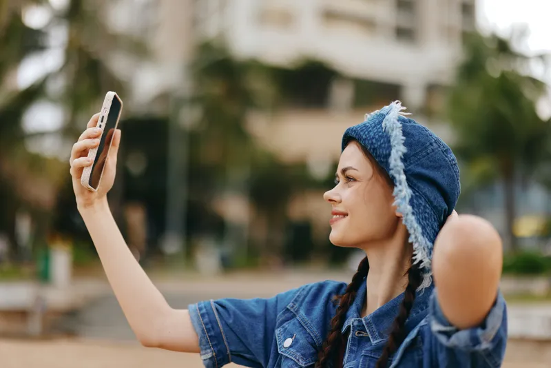 Счастливая молодая женщина делает селфи на смартфон на открытом воздухе