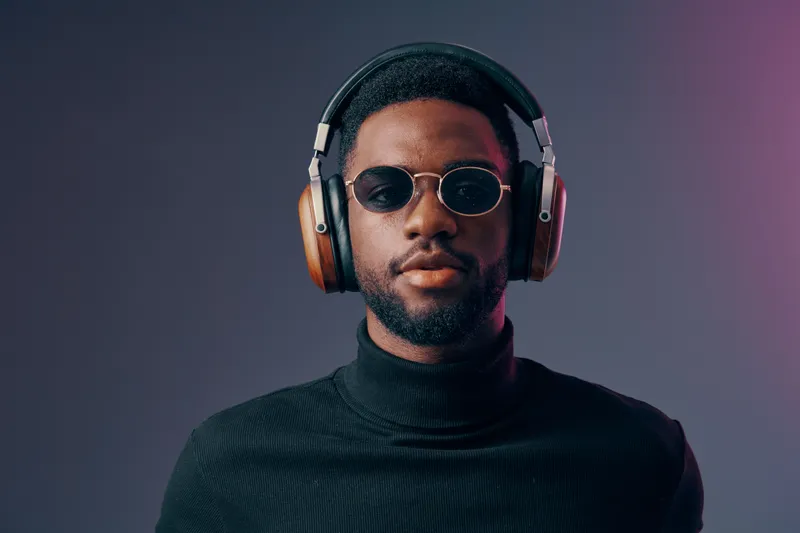 Stylish Black man wearing headphones and sunglasses, exuding confidence against a colorful gradient background, perfect for music and fashion themes