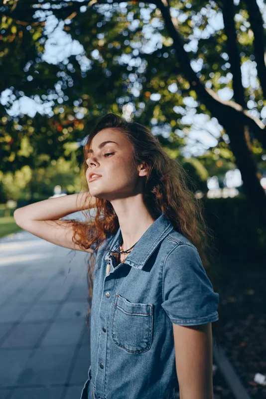 lifestyle woman in modern boho-western denim street style enjoys outdoor moment with natural light and film color tones enhancing relaxed summer vibe