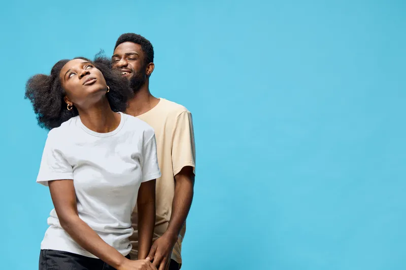 Happy couple enjoying each other s company against a bright blue background, showcasing love and joy in their connection through expressive emotions and casual clothing