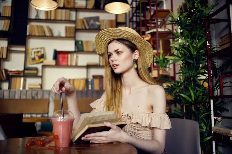 Женщина читает книгу, отдыхая в кафе, наслаждаясь напитком