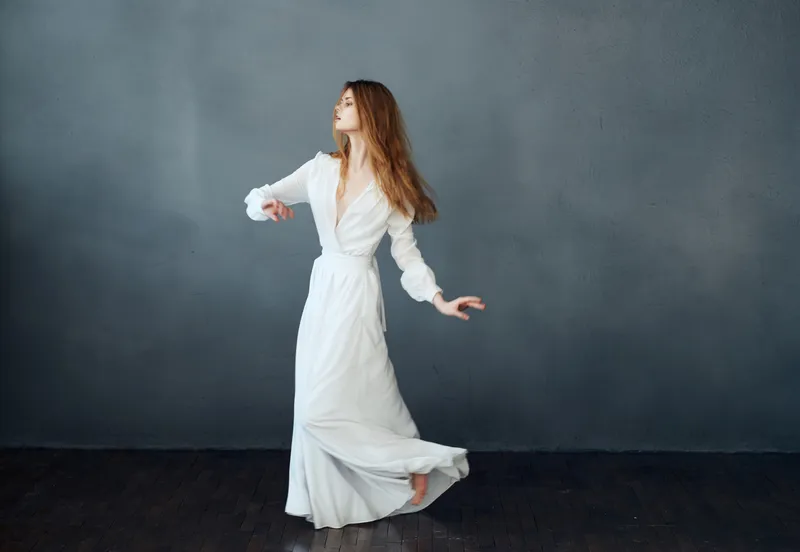 Женщина босиком в белом платье танцует на изолированном фоне, романтика
