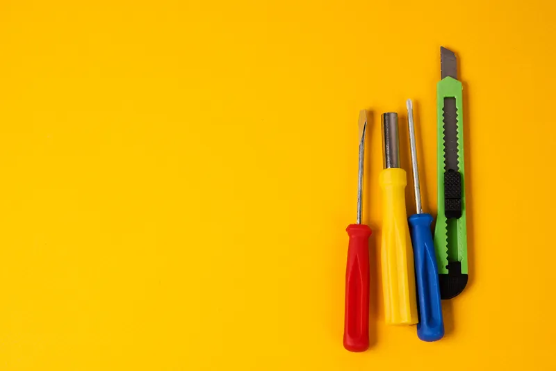 Отвёртки и строительные инструменты на жёлтом фоне