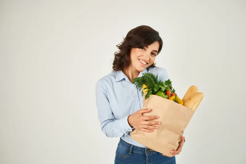 Симпатичная женщина с пакетом продуктов из супермаркета, крупный план