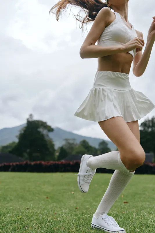Fit young woman in sporty attire jogging in a green field, showcasing a healthy lifestyle with an active and energetic vibe