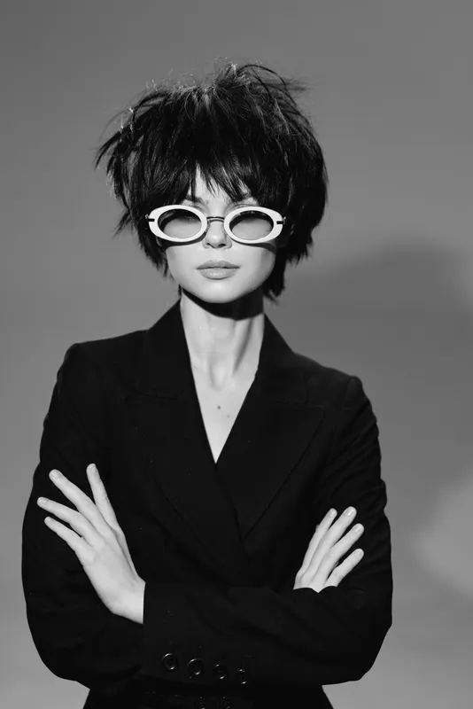 Stylish woman in black suit and white sunglasses with short hair in black and white portrait