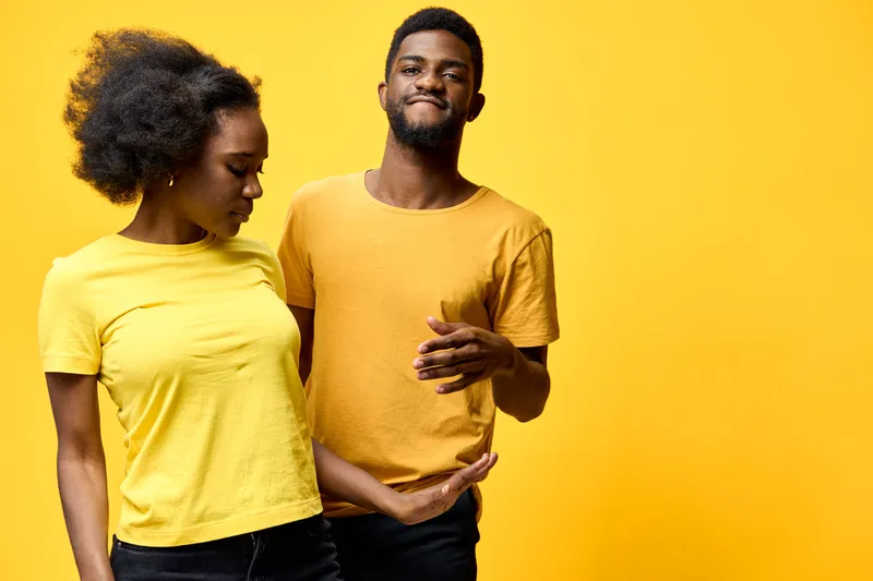 A joyful African couple in matching yellow t shirts poses against a vibrant yellow background, showcasing a fun and playful mood, perfect for lifestyle themes