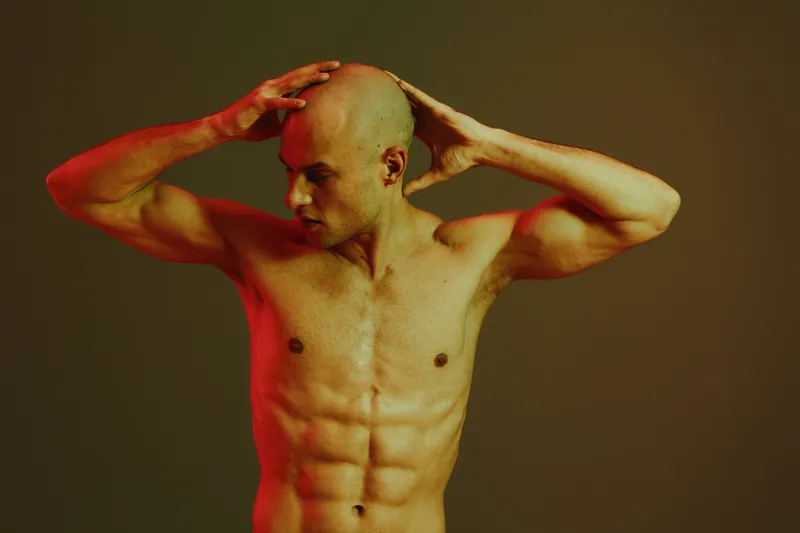 Muscular man expressing strength and determination in a striking pose, featuring dramatic lighting and a vibrant color palette. Ideal for fitness and motivation themes.