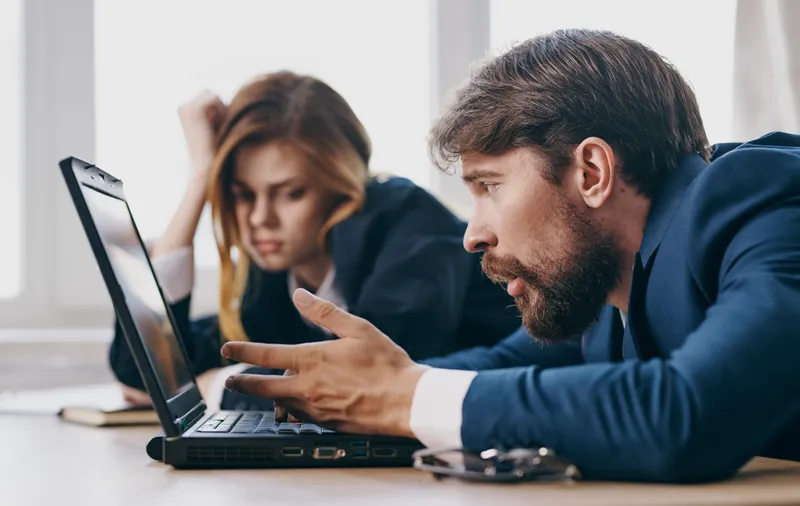 Уставшие мужчина и женщина на работе — коллеги за ноутбуком, профессионалы
