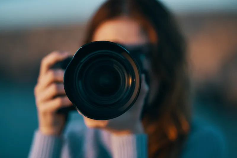 Портрет женщины-фотографа с профессиональной камерой на открытом воздухе в горах