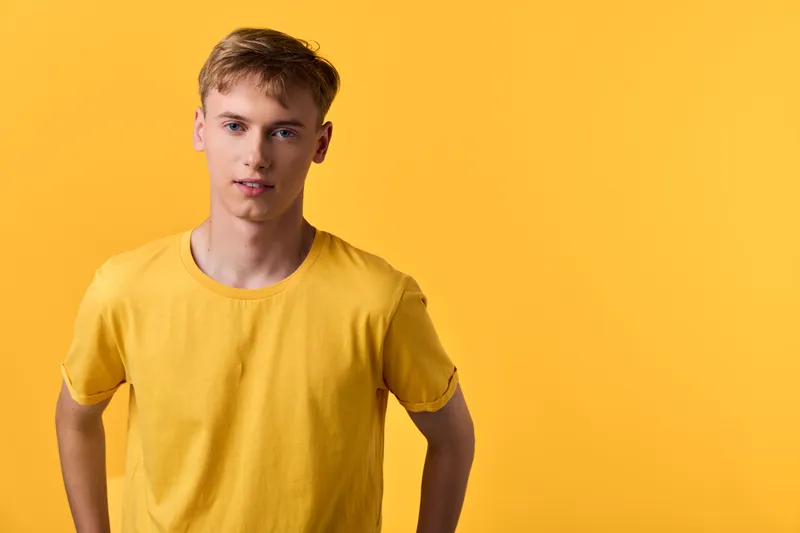Man, young, yellow shirt, studio model pose against bold background, casual apparel, fashion, cheerful confidence, clean simple lines, minimalist vibe, bright lighting