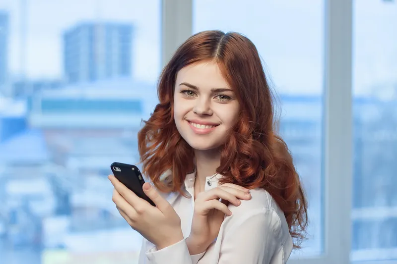 Женщина в рубашке с телефоном в руке — технологии, профессионализм