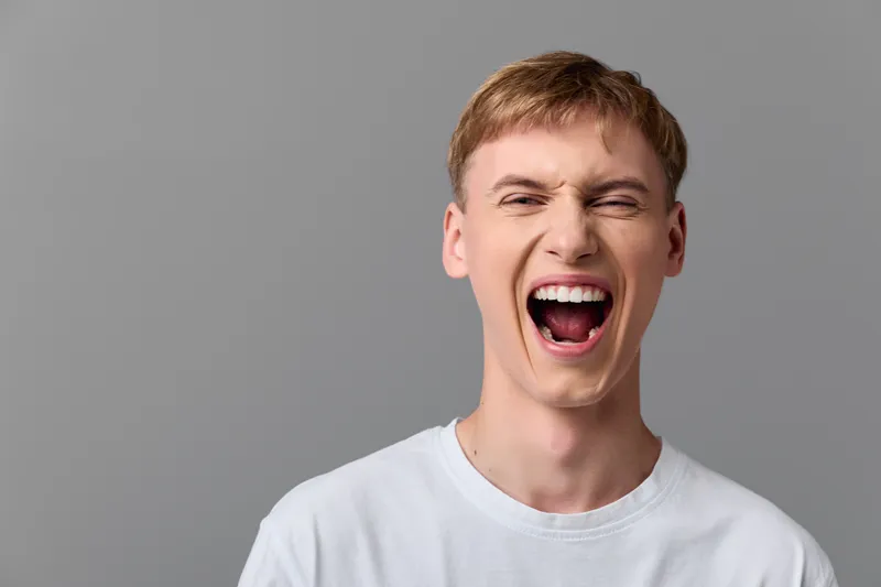 Shouting, excited man with open mouth expressing intense energy and joy in a studio setting, capturing bold emotion, dynamic facial expression, and expressive lifestyle moment for advertising and
