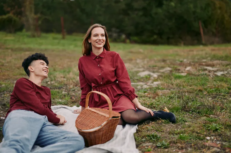 An authentic moment outdoors featuring two relaxed individuals on a blanket, conveying genuine connection, casual charm, and everyday elegance in natural light.