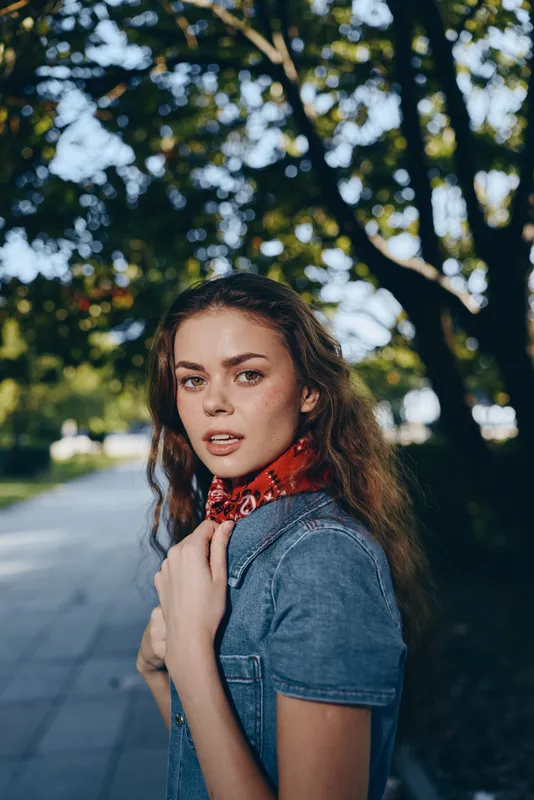 Lifestyle woman in modern boho-western denim street style with film color tones, featuring casual clothing and natural outdoor background in soft focus.