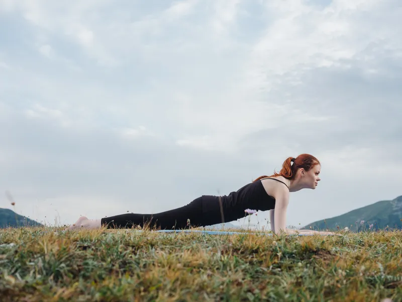 Спортивная женщина занимается йогой и фитнесом на открытом воздухе в горах