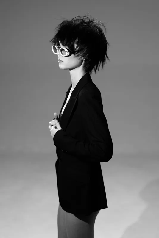 Black and white portrait of fashion woman wearing sunglasses and blazer with stylish hairstyle in studio setting
