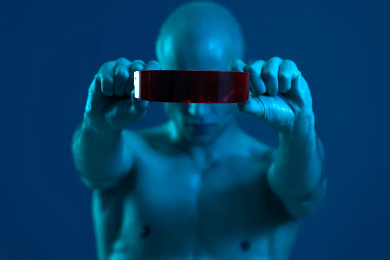 A striking image of a focused man with a bold red accessory, illuminated by blue light, creating a captivating black and white effect.